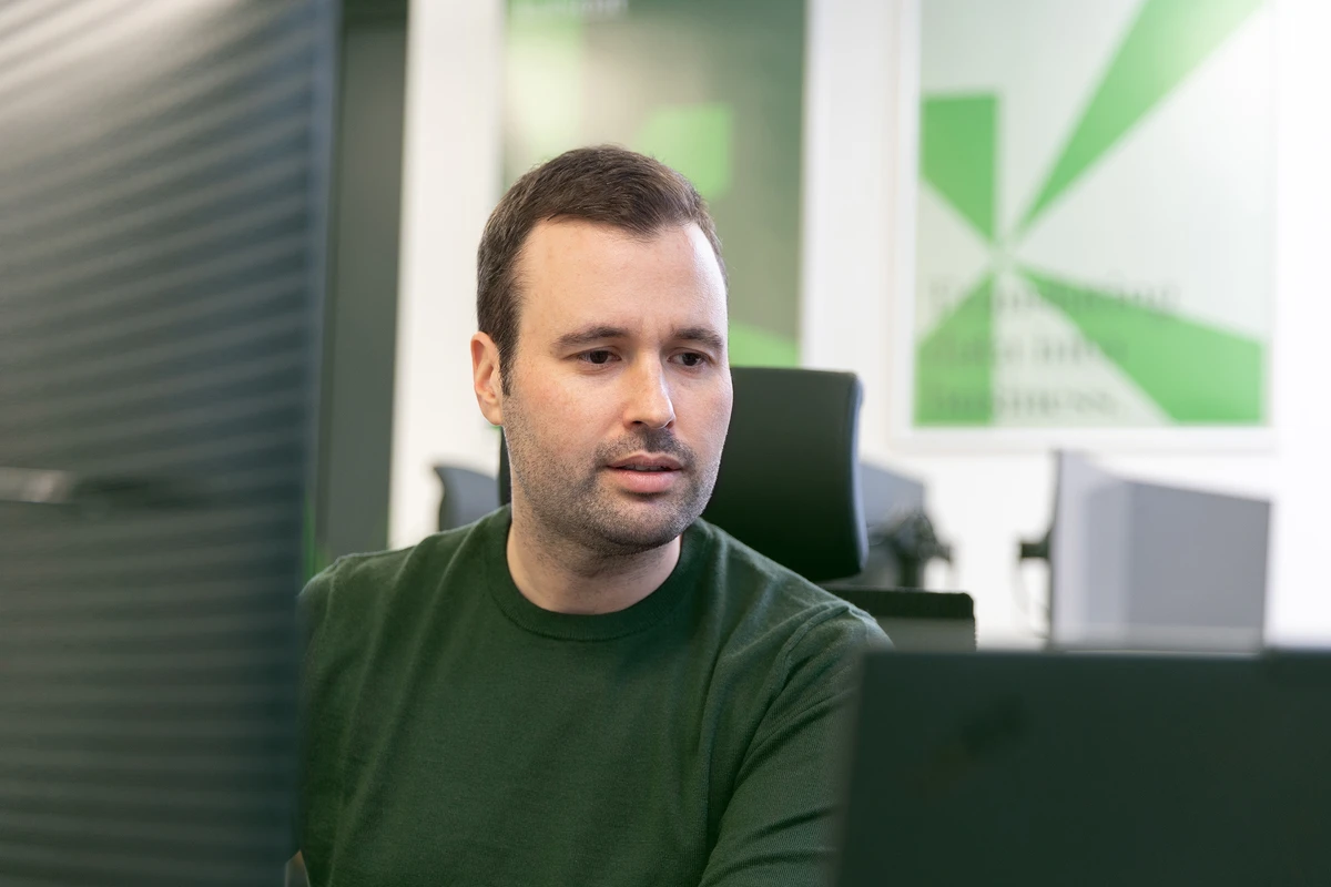 IT-Consultant baut datengetriebene Softwarelösungen. Person sitzt an einem Schreibtisch und blickt auf einen Monitor.