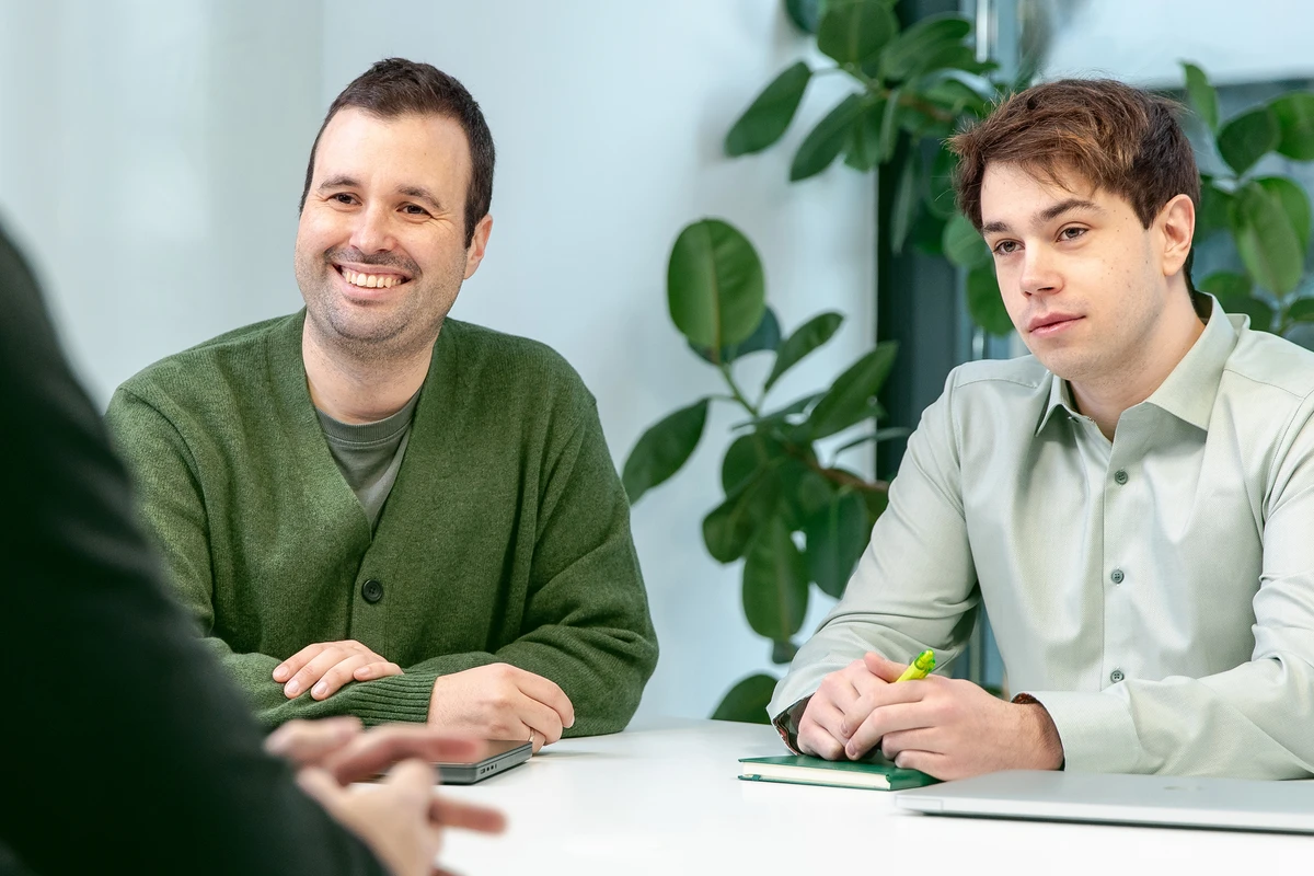 Moderne IT-Beratung und Data Consulting für Unternehmen. Drei Personen sitzen an einem Tisch und unterhalten sich in einem Meeting.