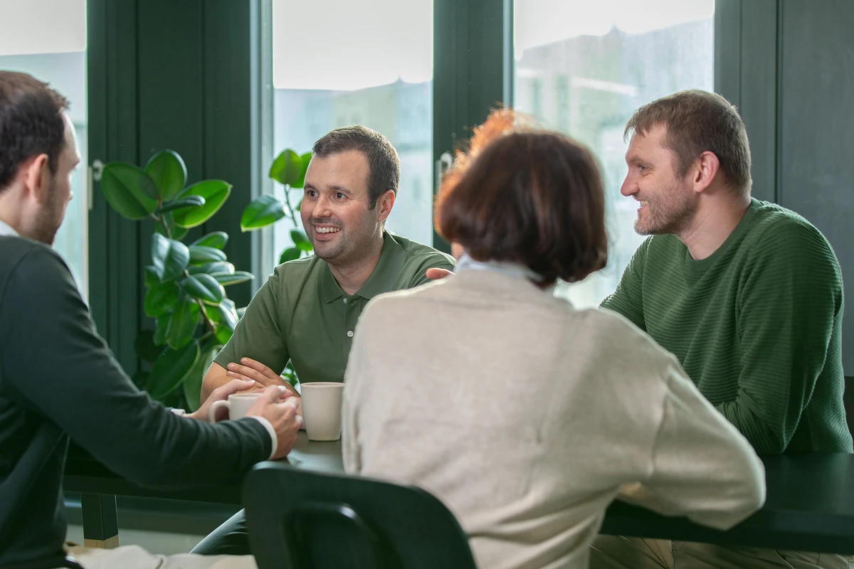 Mehrere Personen sitzen an einem Tisch und unterhalten sich in einem Besprechungsraum.