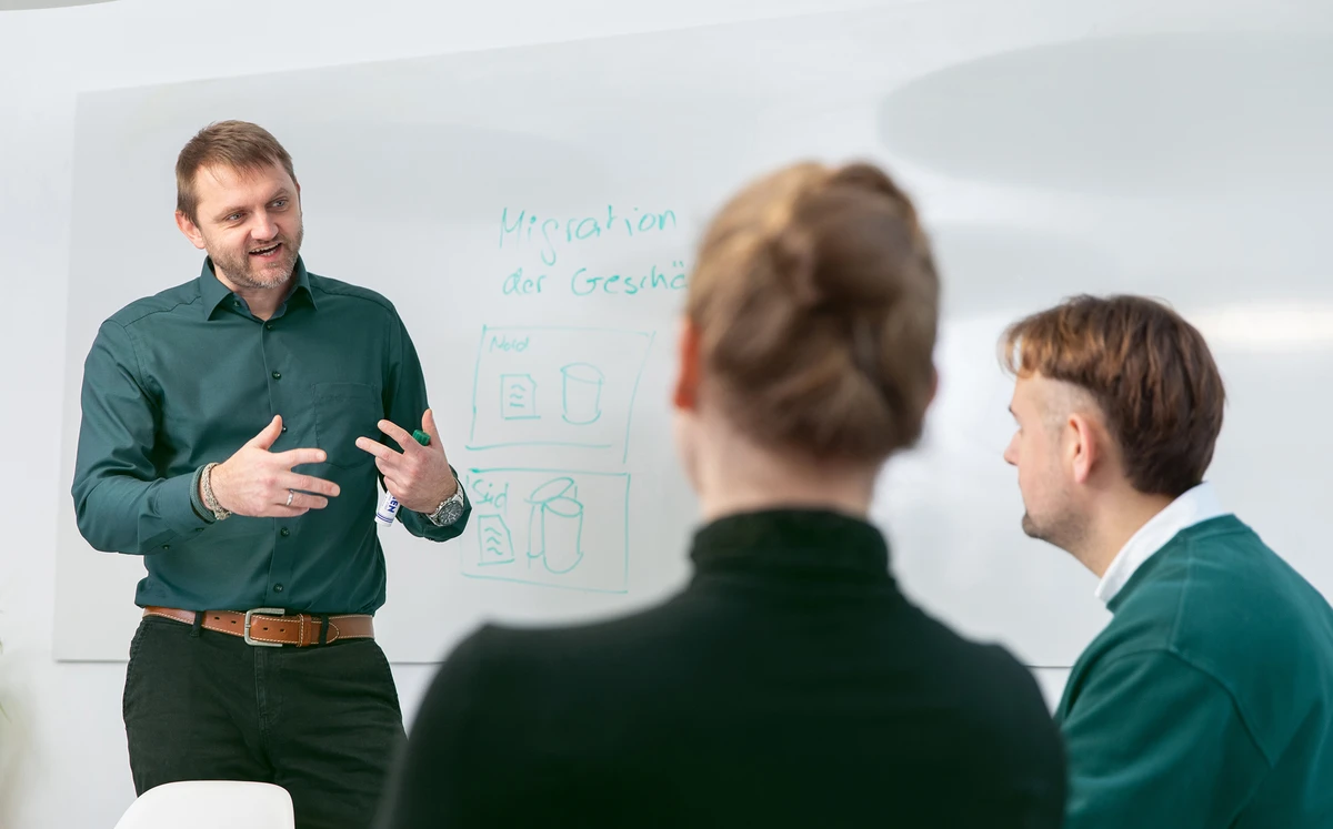 Workshop bei kubidat zur Datenmigration und IT-Strategieentwicklung. Person steht vor einem Whiteboard und erklärt Zeichnungen und Notizen.